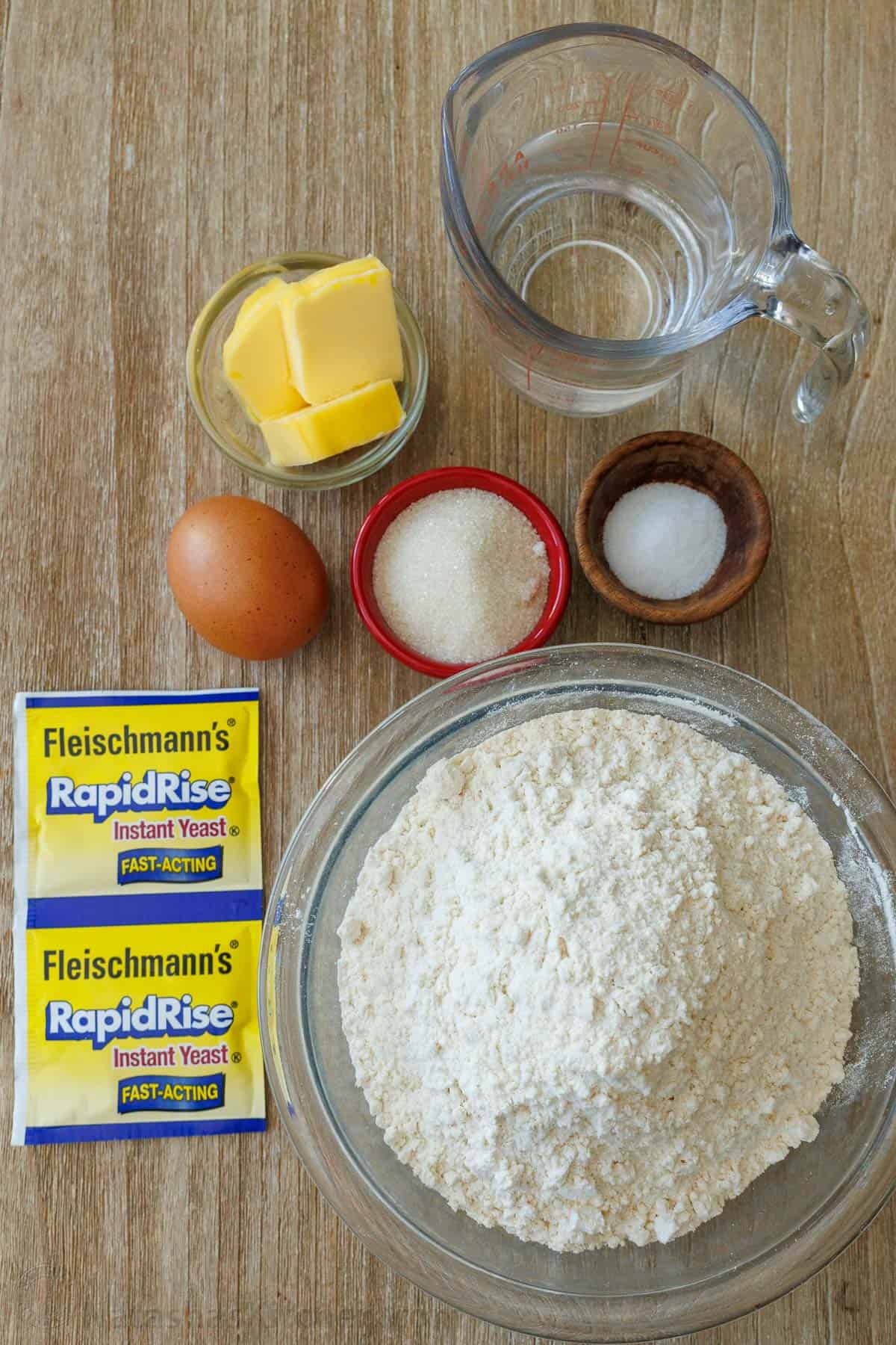 ingredients for making homemade bread for burgers and sandwhiches including water, butter, egg, sugar, salt, pepper, instant yeast and flour