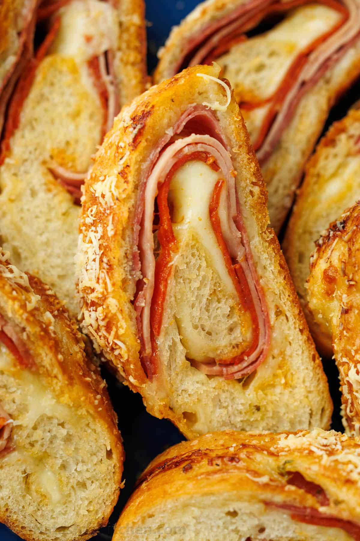 Stromboli sliced into pinwheels showing ham, pepperoni, salami, and cheese