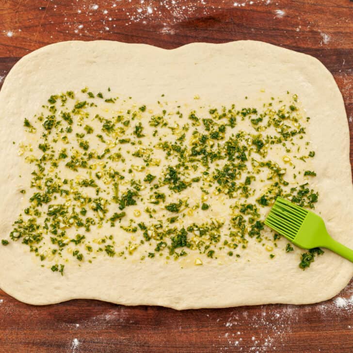 Homemade pizza dough rolled into a rectangle and brushed with olive oil, parsley, garlic