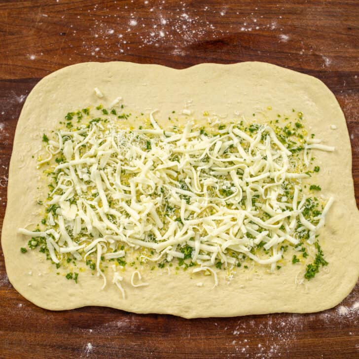 Homemade pizza dough rolled into a rectangle and topped with olive oil, parsley, garlic and mozzarella cheese