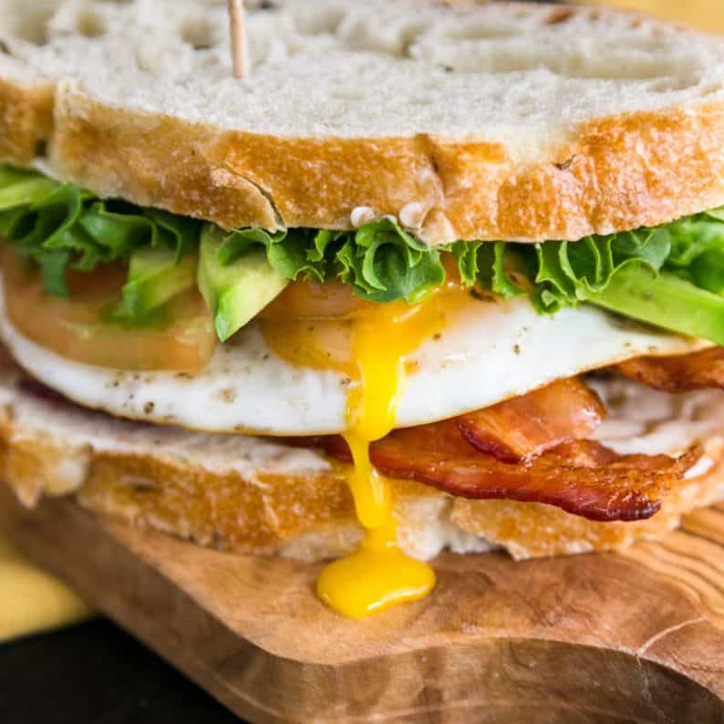 A close up of a breakfast BLT sandwich on a cutting board