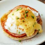 Eggs Benedict with Hollandaise sauce served on a white plate